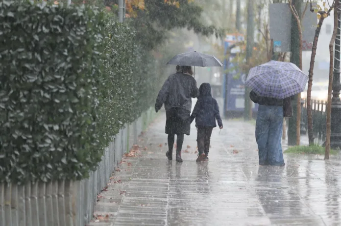 Σύννεφα και βροχή πάνω από αστικό τοπίο, προειδοποίηση κακοκαιρίας